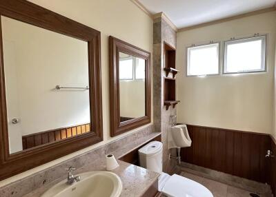 Modern bathroom with double mirrors, sink, toilet, and natural light