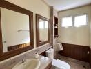 Modern bathroom with double mirrors, sink, toilet, and natural light