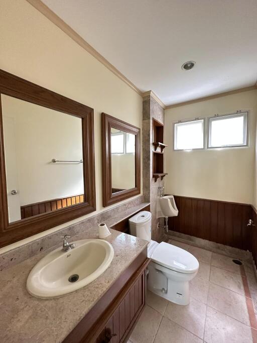 Modern bathroom with double mirrors, sink, toilet, and natural light