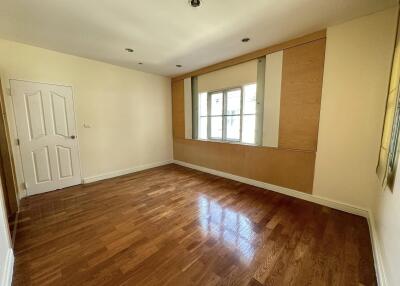 Spacious bedroom with wooden floor and large window