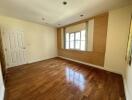 Spacious bedroom with wooden floor and large window