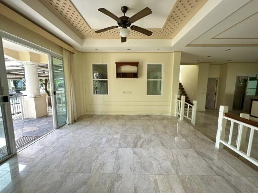 Spacious living room with ceiling fan, sliding glass door, and staircase