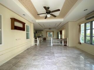 Spacious living room with marble floors, ceiling fan, and large windows