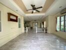 Spacious living room with marble floors, ceiling fan, and large windows