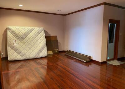 Empty bedroom with hardwood floors and a mattress against the wall