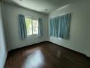 Empty bedroom with two windows and blue curtains