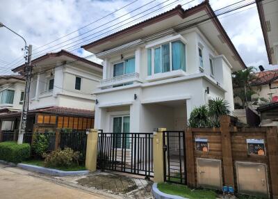 Exterior view of a modern two-story house with a gate and surrounding houses