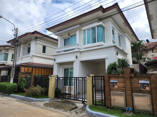 Exterior view of a modern two-story house with a gate and surrounding houses