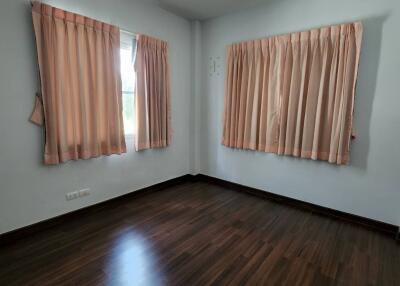 Empty bedroom with wooden flooring and pink curtains