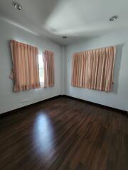 Empty bedroom with wooden flooring and pink curtains