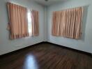 Empty bedroom with wooden flooring and pink curtains