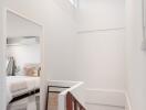 Brightly lit hallway with wooden staircase and view into a bedroom