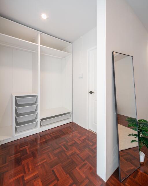 Spacious bedroom with empty open wardrobes and a large mirror