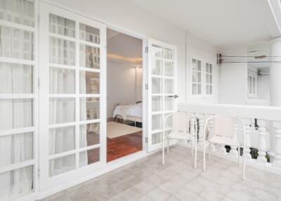 Balcony with white chairs and French doors leading into a bedroom