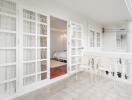 Balcony with white chairs and French doors leading into a bedroom