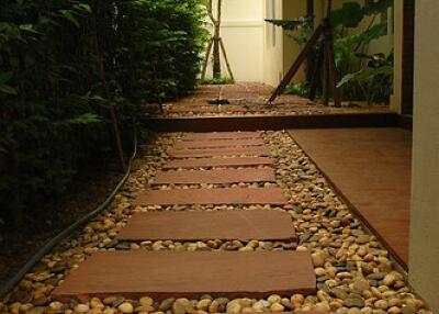 A walkway with stone steps and pebbles next to a garden