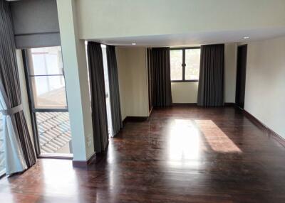 Spacious living room with wooden floors and large windows.