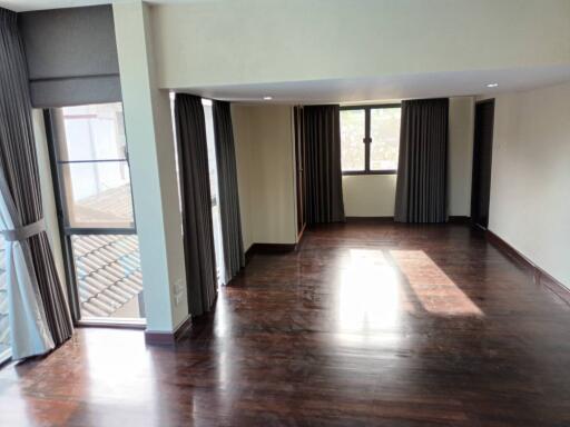 Spacious living room with wooden floors and large windows.