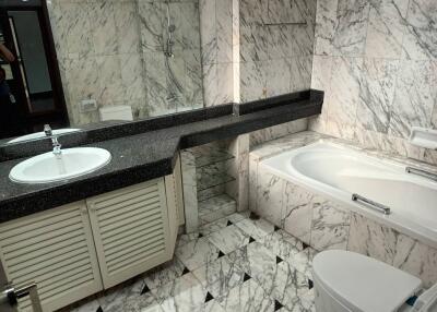 Modern bathroom with marble tiles, bathtub, and vanity