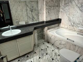 Modern bathroom with marble tiles, bathtub, and vanity