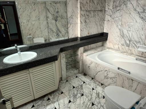 Modern bathroom with marble tiles, bathtub, and vanity