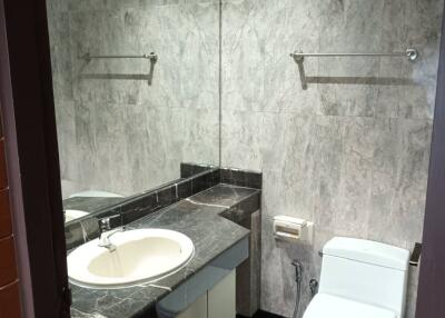 Modern bathroom with marble tiles, sink, and toilet