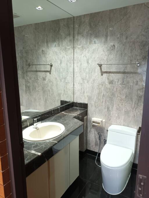 Modern bathroom with marble tiles, sink, and toilet