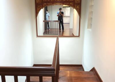 Staircase with wooden steps and railing, decorative mirror frame, and small rug