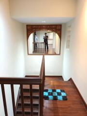 Staircase with wooden steps and railing, decorative mirror frame, and small rug