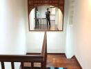 Staircase with wooden steps and railing, decorative mirror frame, and small rug