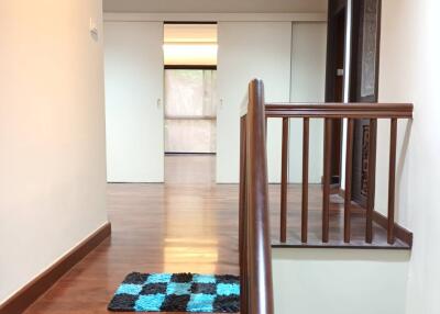 Bright hallway with wooden stairs and a checkered mat