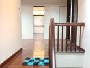 Bright hallway with wooden stairs and a checkered mat