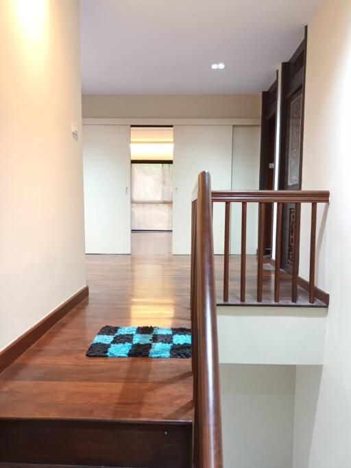 Bright hallway with wooden stairs and a checkered mat