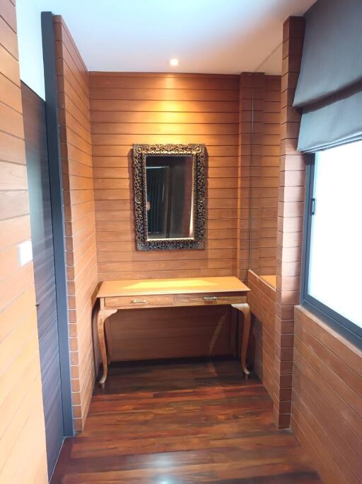 Cozy bedroom corner with wooden panel walls and a dressing table