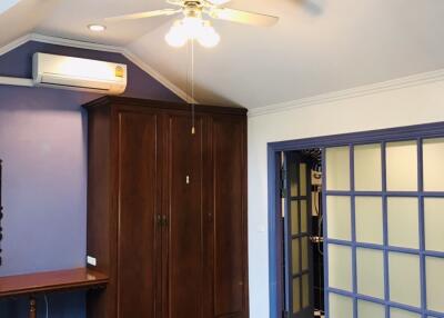 Spacious bedroom with wooden wardrobe and ceiling fan