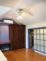 Spacious bedroom with wooden wardrobe and ceiling fan