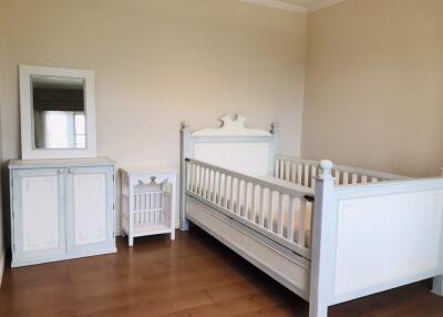 Crib in a nursery room with a cabinet and a mirror