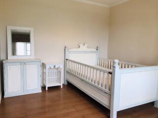 Crib in a nursery room with a cabinet and a mirror