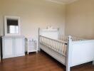 Crib in a nursery room with a cabinet and a mirror