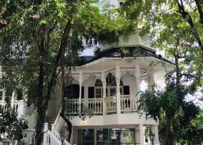 Front view of a house with a white picket fence and lush trees