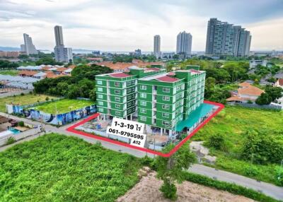 Aerial view of a green residential building surrounded by greenery and other buildings