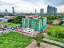 Aerial view of a green residential building surrounded by greenery and other buildings