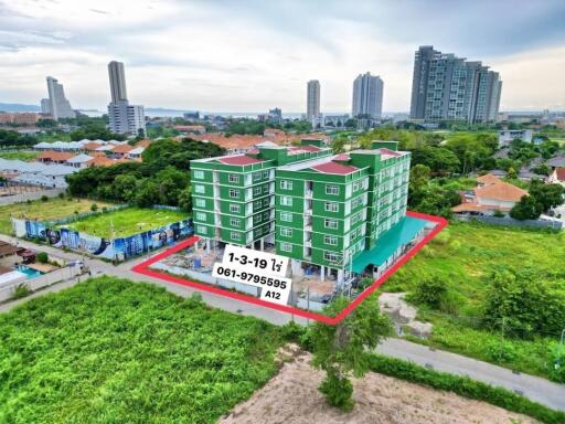 Aerial view of a green residential building surrounded by greenery and other buildings