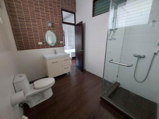 Modern bathroom with a glass shower, toilet, and sink.