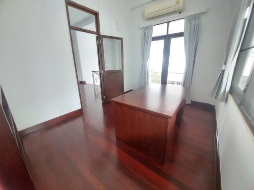 A minimalist home office with wooden flooring and large windows.