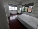 Bedroom with large windows and dark wood floors