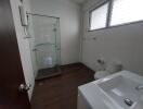 Modern bathroom with glass shower, sink, and toilet