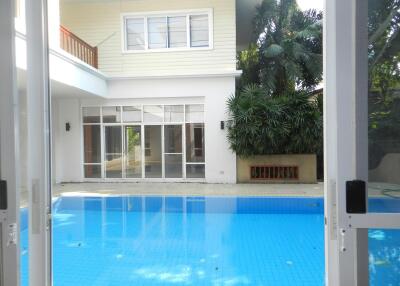 Outdoor pool area with view of a two-story house