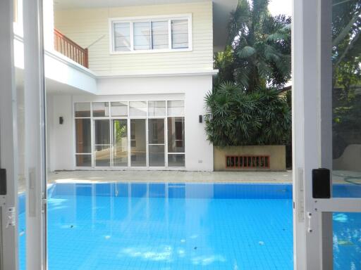 Outdoor pool area with view of a two-story house