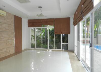 Bright living room with large windows and glass doors opening to a patio with a pool